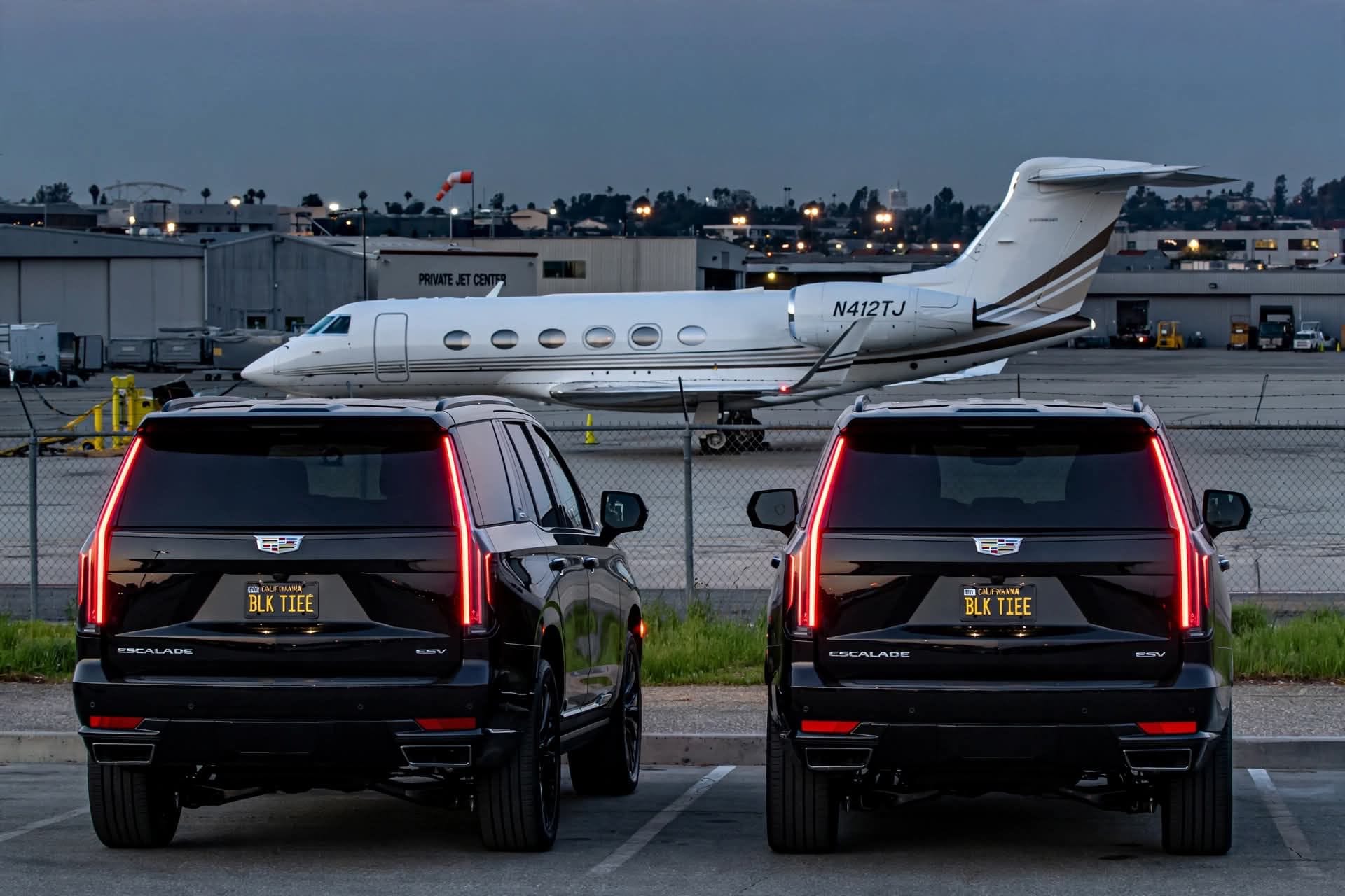 Two black Cadillac Escalades waiting at a private airport terminal